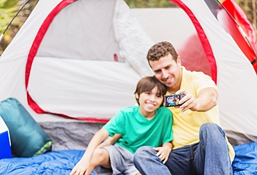 Father and son (12-13) taking selfie in front of tent, Jupiter, Florida