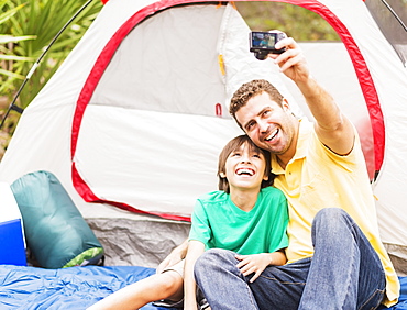 Father and son (12-13) taking selfie in front of tent, Jupiter, Florida