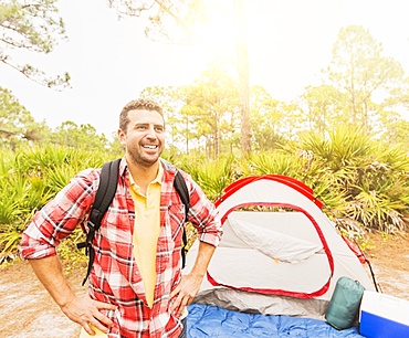 Man with backpack in front of tent, Jupiter, Florida