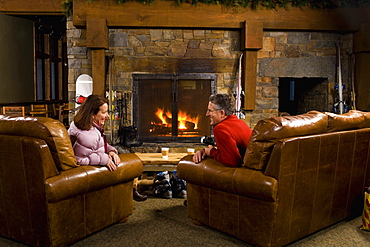 Man and woman chatting in front of fireplace, Whitefish, Montana, USA