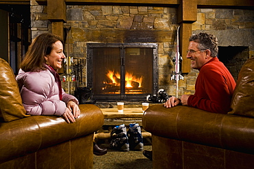 Man and woman chatting in front of fireplace, Whitefish, Montana, USA