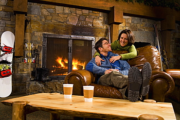 Man and woman hanging out in front of fireplace, Whitefish, Montana, USA