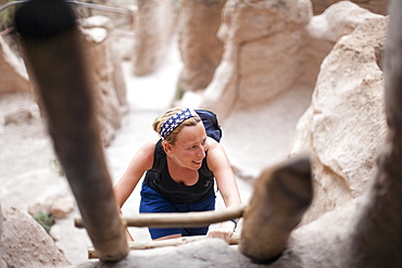 Woman walking up ladder, Bandelier National Monument Los Alamos, New Mexico