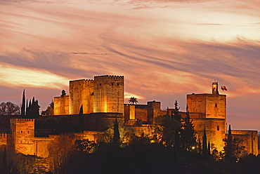 Illuminated castle at dusk, pastel colored clouds in sky, Alhambra, Granada, Spain 