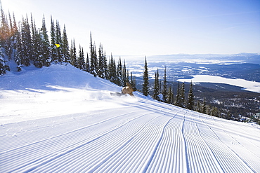 Snowboarder on side of ski slope, Whitefish, Montana, USA