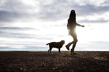 Woman walking with dog at sunrise, Colorado, USA