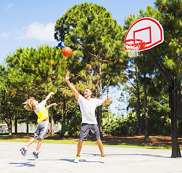 Boy (8-9) playing basketball with his brother