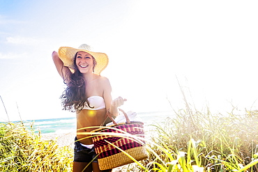 Woman in sunhat carrying basket on beach, Jupiter, Florida,USA