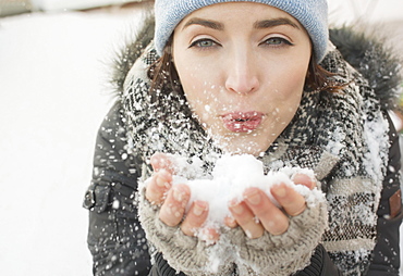 Woman blowing snow towards camera