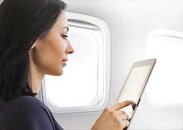 Young woman using tablet on plane