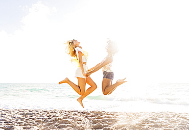 Female friends jumping on beach, USA, Florida, Jupiter