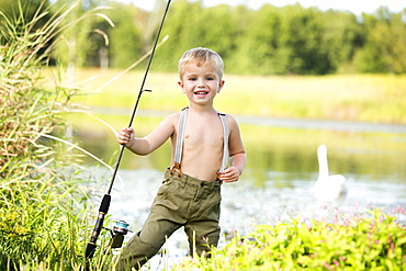 Smiling boy (4-5) holding fishing rod, USA, New Jersey, Oldwick