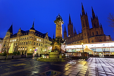 Monument on illuminated square, Germany, Hesse, Wiesbaden, Rathaus and Marktkirche