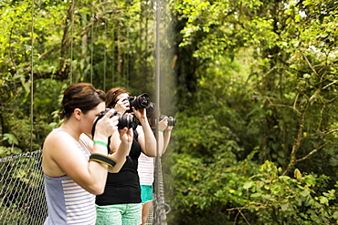 Young women photographing in forest, Costa Rica