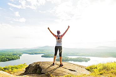 Young woman standing on top of mountain with outstretched arms, rear view, USA, Maine, Camden