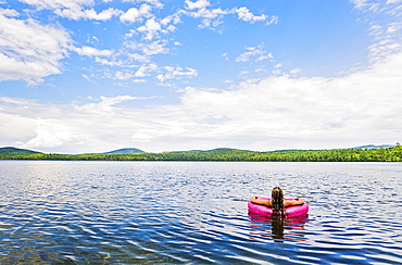 Young woman relaxing on lake in pool raft