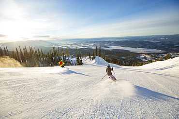 Two people on ski slope at sunlight, USA, Montana, Whitefish