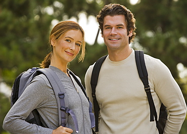 Couple wearing backpacks in woods