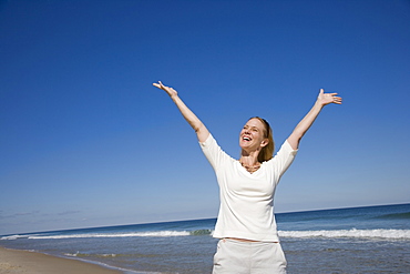 Woman with arms raised at beach