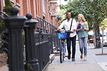 Couple walking with bicycle and exercising mat