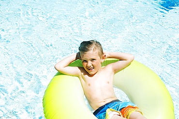 Boy (4-5) relaxing in inflatable ring