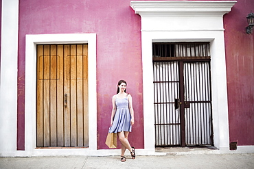 Puerto Rico, San Juan, Woman with shopping bag standing in front of pink building