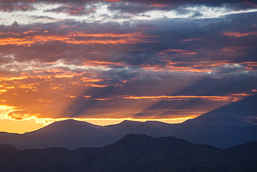 USA, Colorado, Denver, Setting sun shining through clouds over Front Range