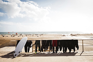 Wetsuits and surfboard on railing at Carcavelos Beach, Carcavelos, Lisbon, Portugal