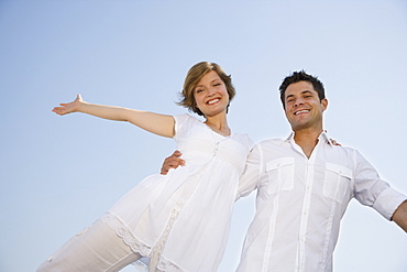 Low angle view of couple with arms outstretched