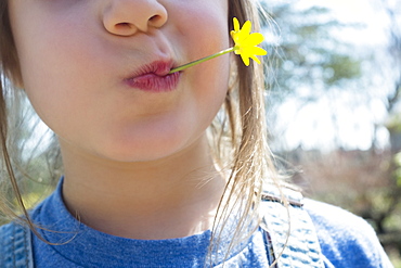 Girl with yellow flower in mouth