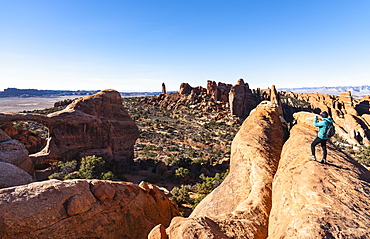 Woman taking photograph while hiking in Arches National Park, Utah, USA