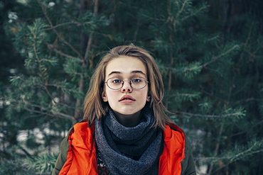 Teenage girl with glasses by pine tree