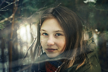 Teenage girl amongst pine branches in winter