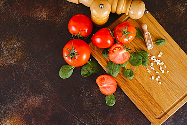 Tomatoes, basil and salt on wooden cutting board