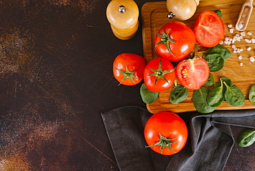 Tomatoes, basil and salt on wooden cutting board