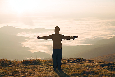 Man with arms outstretched in the Carpathian Mountain Range at sunrise