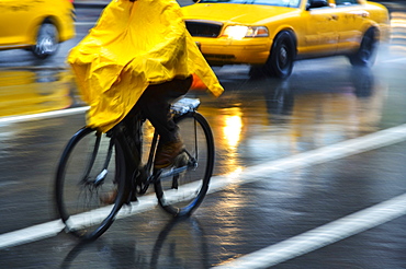 Cyclist in yellow poncho during rain in New York City, USA