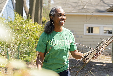 Mature woman volunteer collecting branches in garden