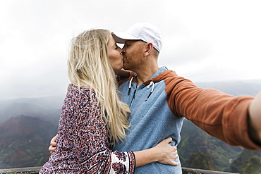 Mid adult couple taking selfie while kissing