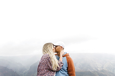 Mid adult couple kissing by mountains in mist