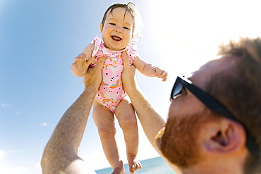 Father holding his baby girl aloft