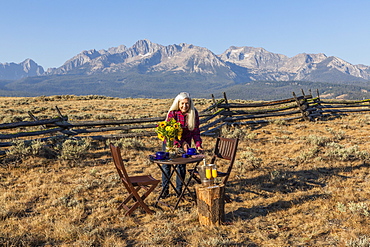 Mature woman setting dining table in field by mountain in Stanley, Idaho