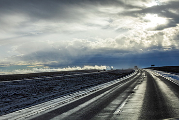 Country road with snow under overcast sky