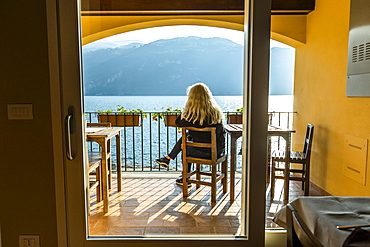 Mature woman sitting on balcony by Lake Como in Lombardy, Italy