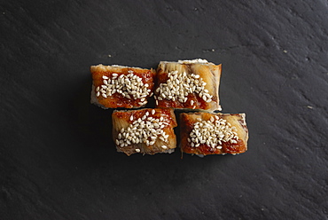 Sushi with sesame seeds on black surface