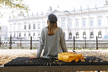 Young woman sitting on park bench near German Historical Museum in Berlin, Germany