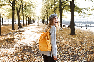 Young woman with yellow backpack in park in Berlin, Germany