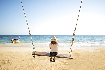 Young woman on swing at beach