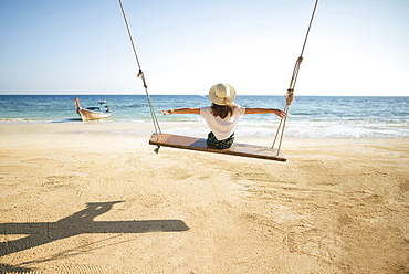 Young woman on swing at beach