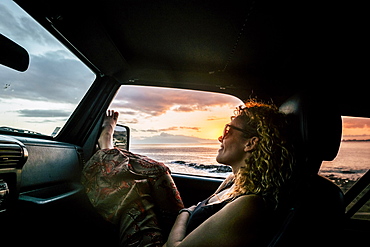 Woman in car with her legs raised watching sunset